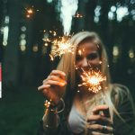 Mädchen steht im Wald und lacht mit Wunderkerzen