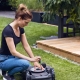 Frau arbeitet mit einem Akku-Rasenroboter nachhaltig im Garten.