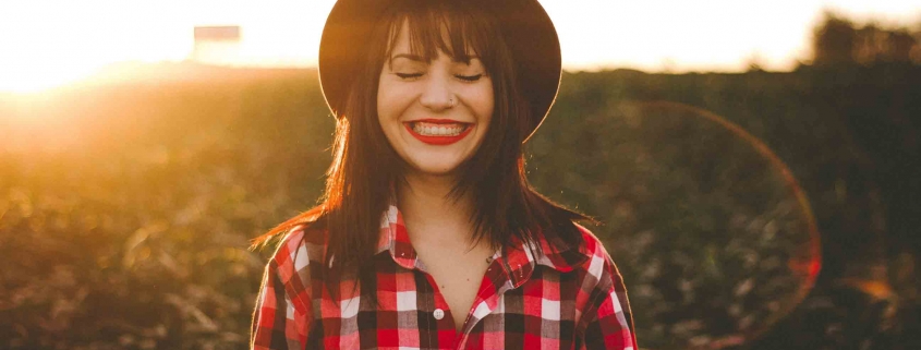 Frau lacht in der Sonne - wir haben 5 Tipps für Dich, wie Du ganz einfach Strom sparen kannst.