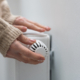 Frau dreht am Heizkörper-Thermostat.